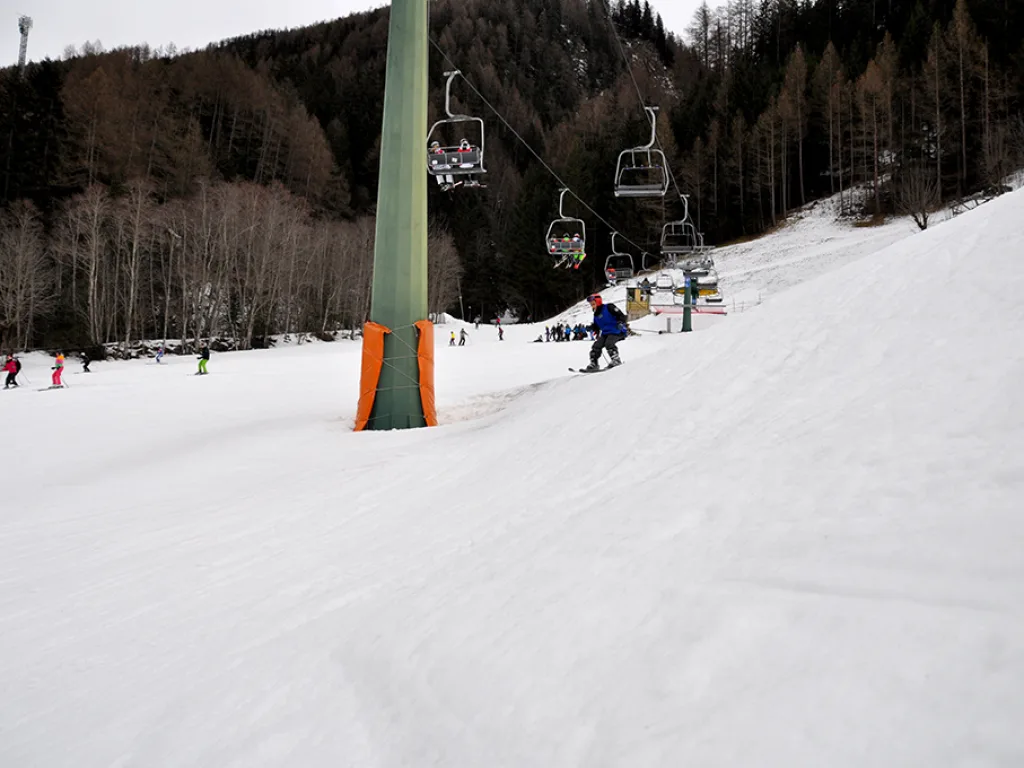 Snowboarder fährt unterhalb der Liftstütze talwärts.